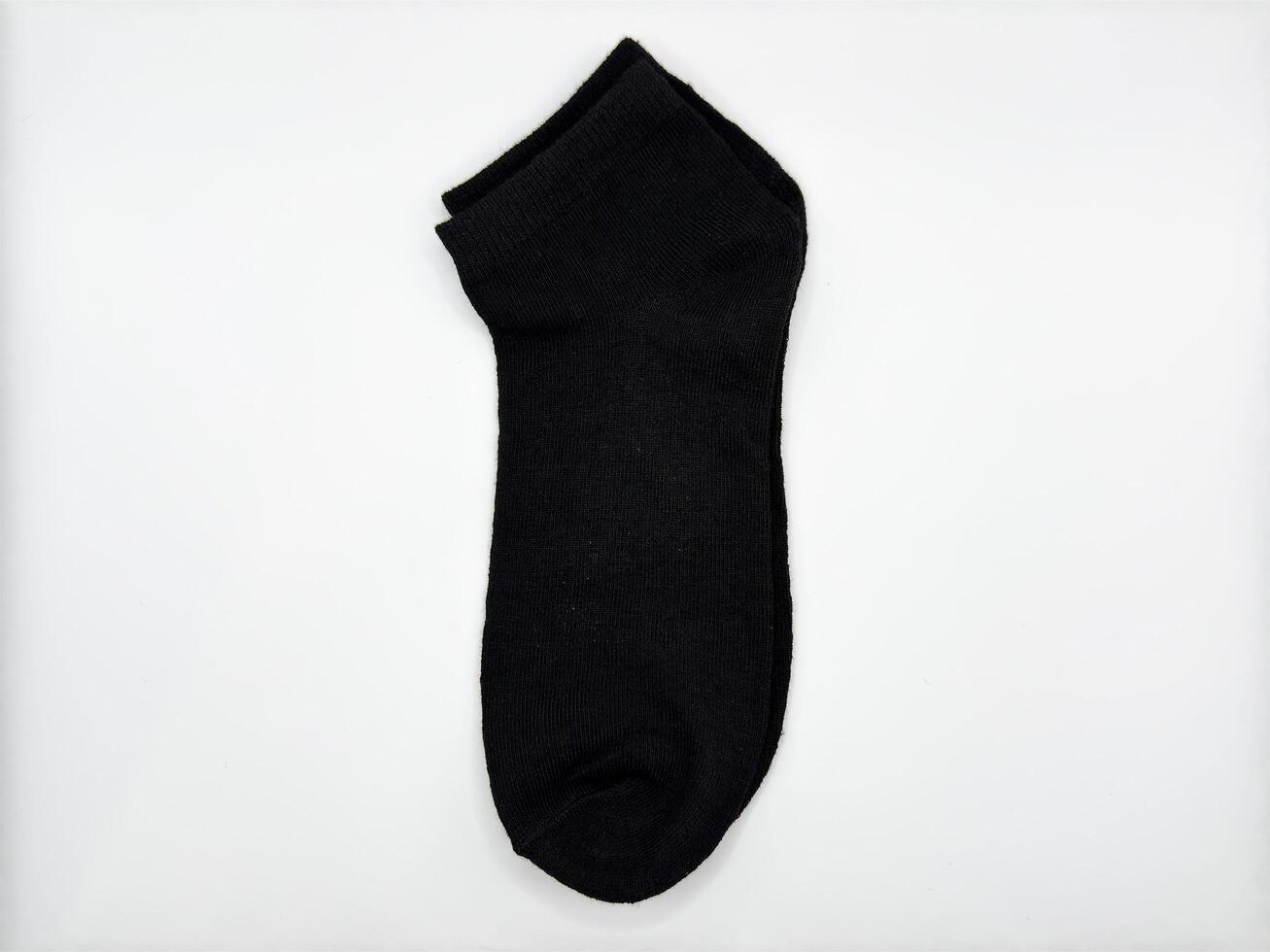 Black short men's socks on a white background one pair lie in the center of the image vertically and turned to the left from the center top view photo