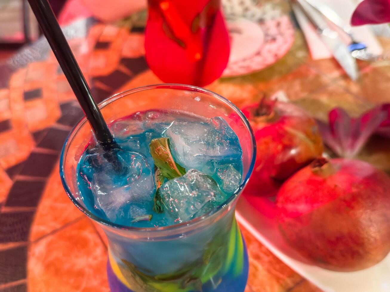 Mahito blue non-alcoholic against a background of ripe pomegranates, copy space. photo