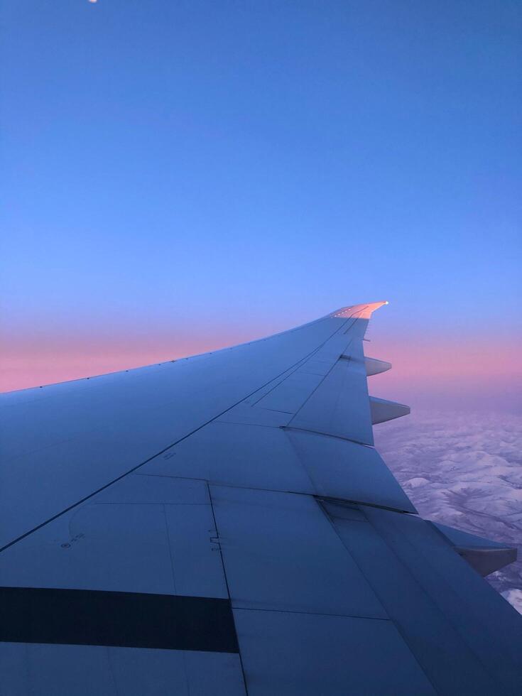 Airplane wing view from airplane window during sunset photo