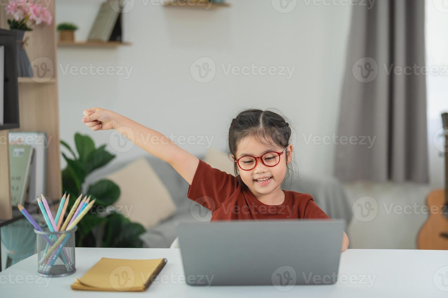 Happy child celebrating success while studying at home using laptop, showcasing joy and enthusiasm in a bright and welcoming environment photo