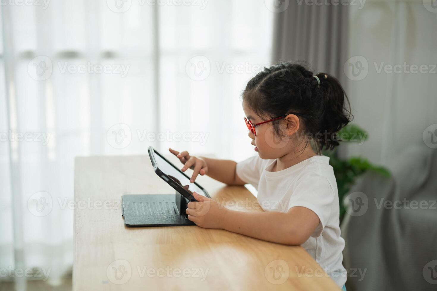 Young child engaging with digital tablet in cozy home environment, focused expression, technology usage for learning and play, cheerful atmosphere photo