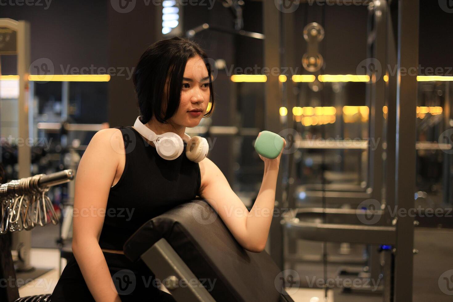 Asian Female Wearing Black Sports Bra doing Lifting Dumbbell Weight Exercise in Sport Fitness Gym. photo