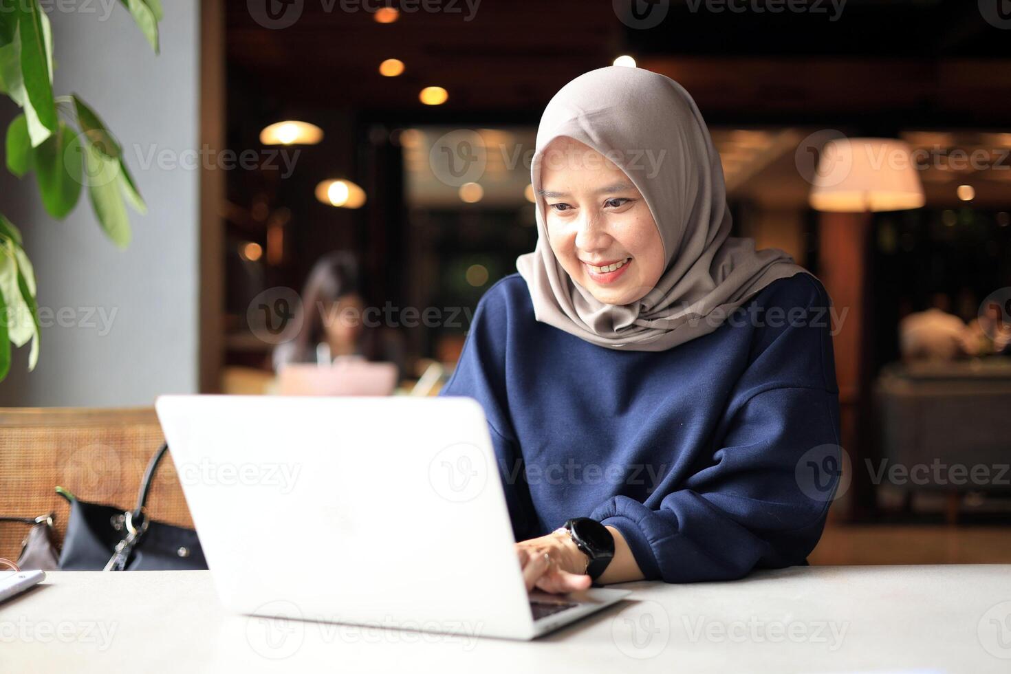 Muslim Asian Women with Hijab Working at a Cafe and using Laptop Computer. photo