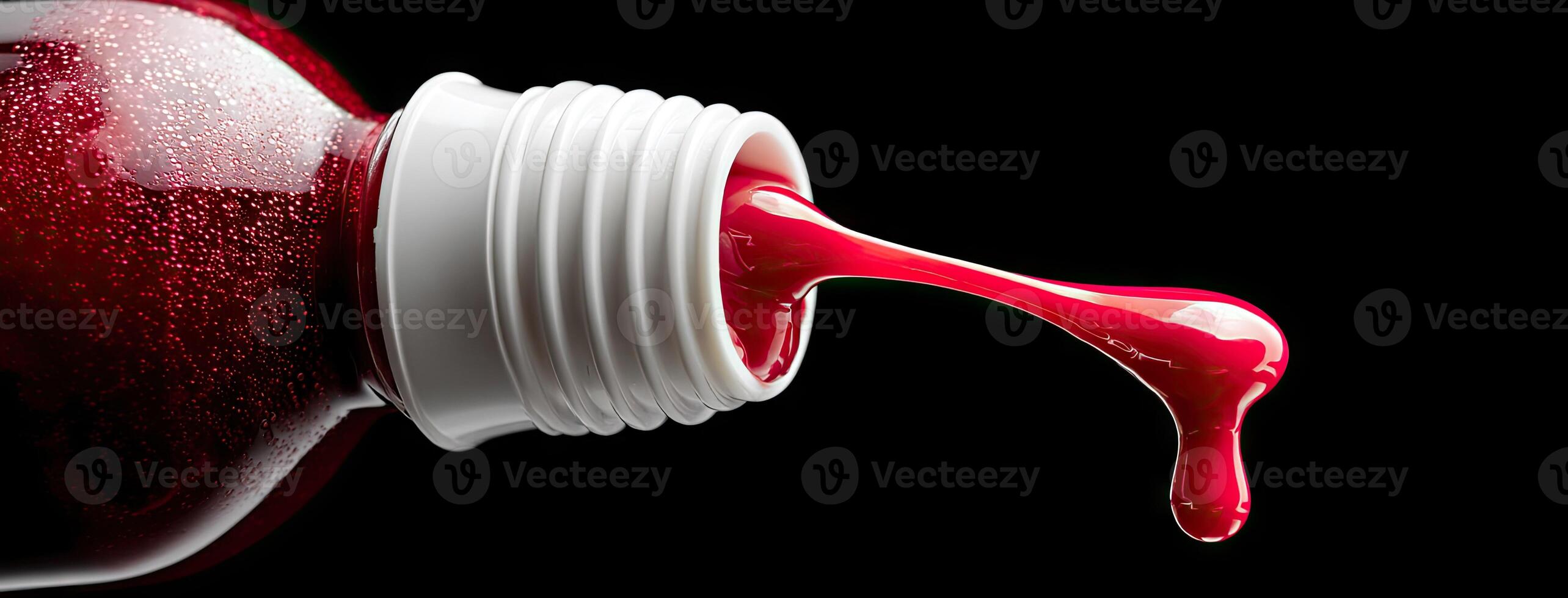 A bottle of red liquid being poured into a glass photo