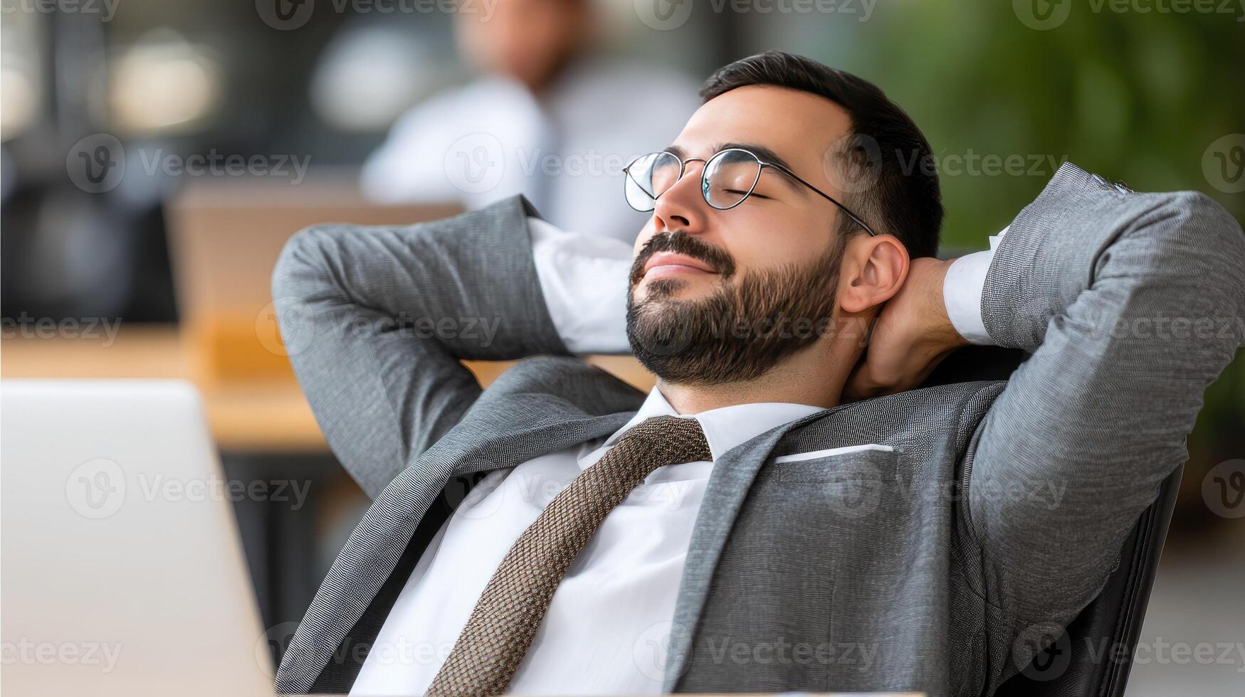 A man in a suit and tie is relaxing in front of a laptop photo