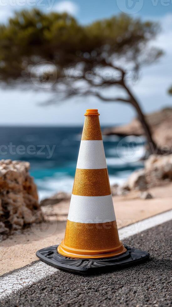 A traffic cone on the side of a road near the ocean photo