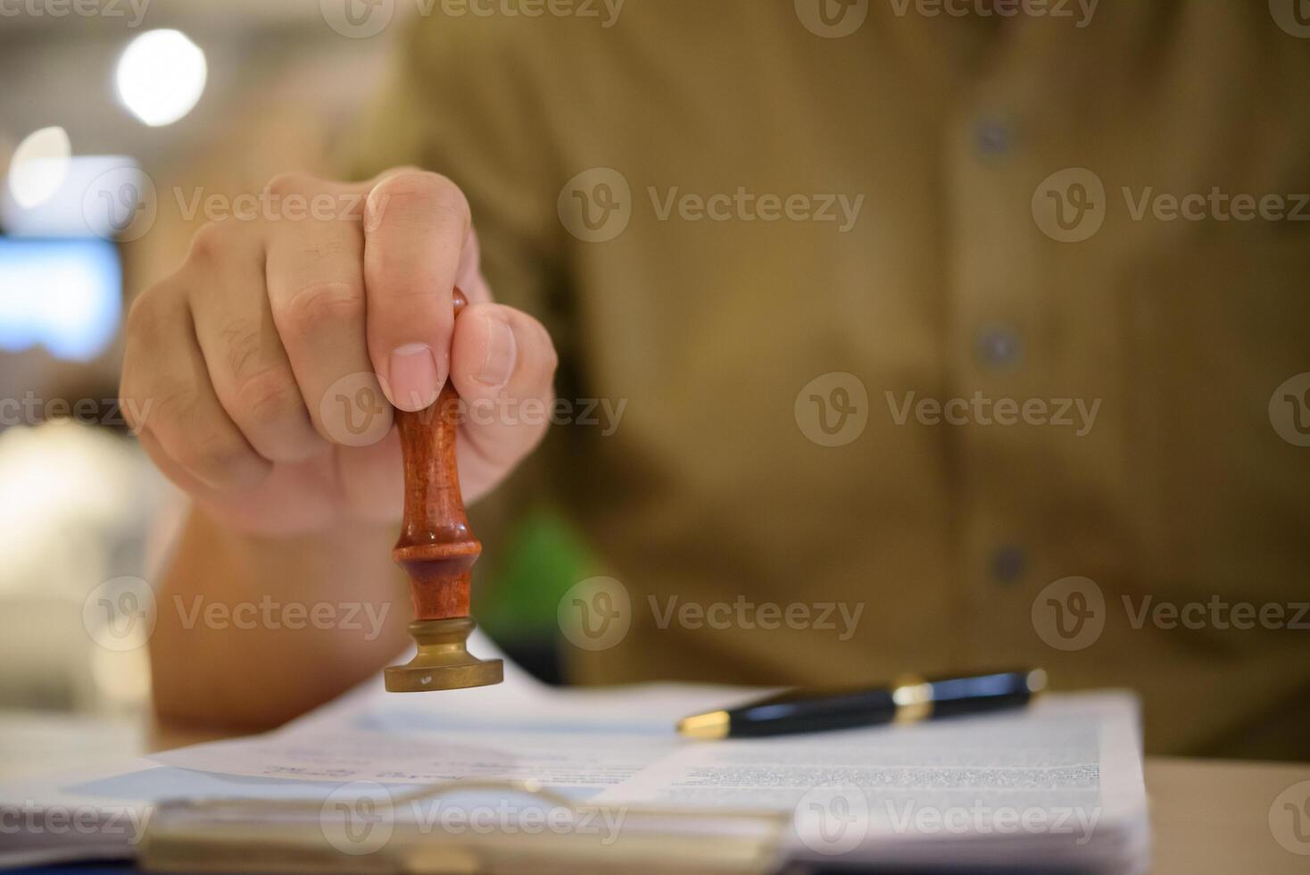 A person holding a wooden stamp on a piece of paper photo