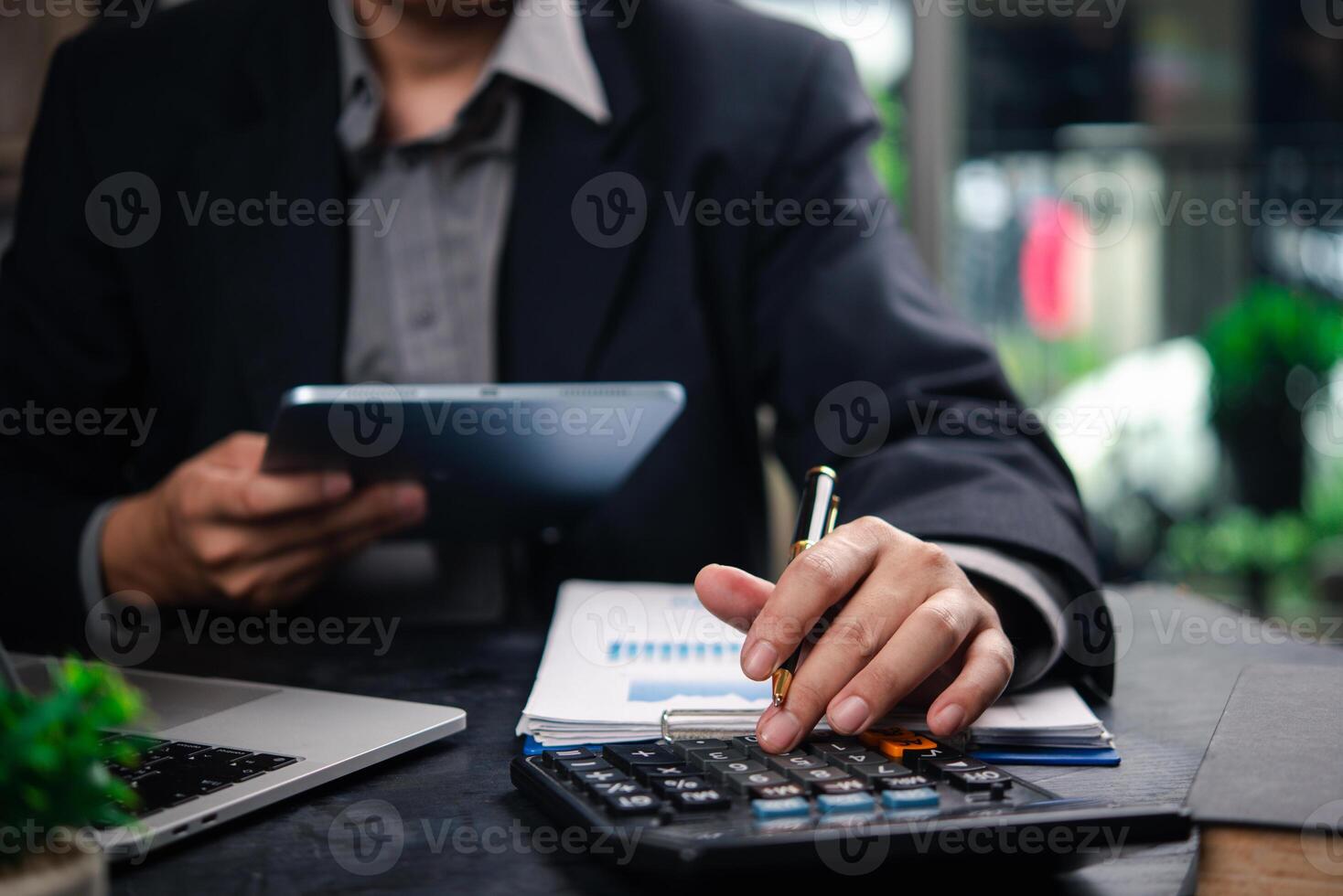 A man in a suit is using a calculator and pen photo