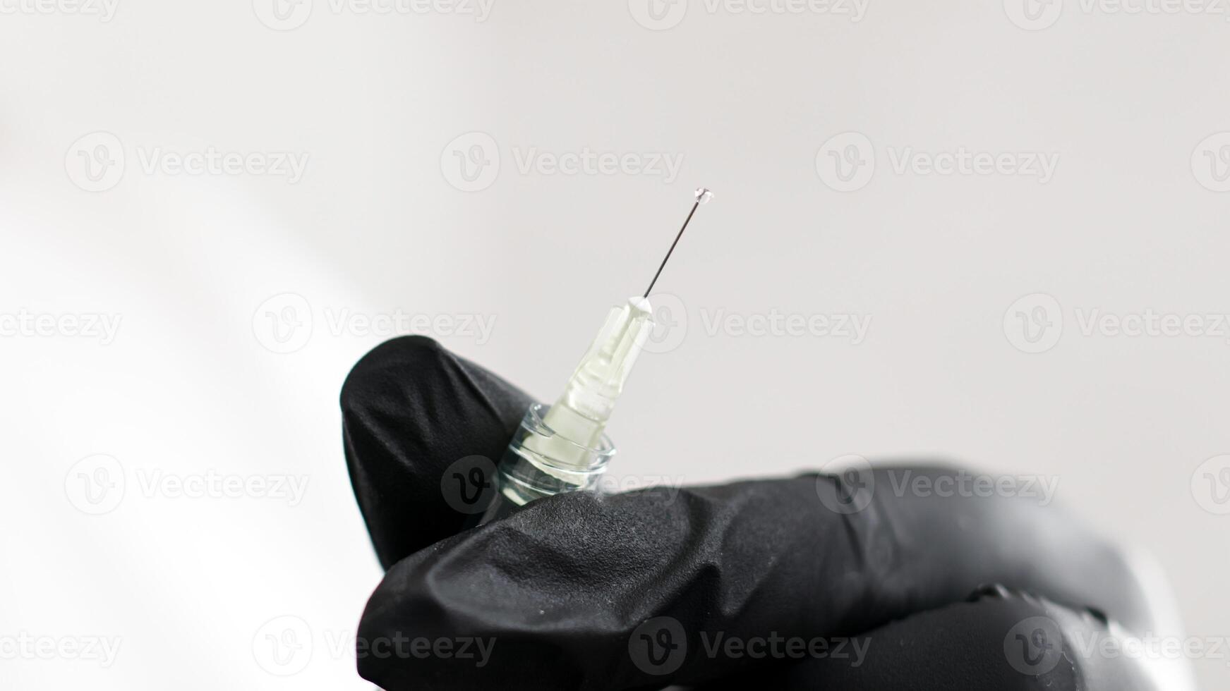 Open syringe needle for injection. Hands in medical gloves preparing a syringe before injection on a white background. Vaccination. Sterile medical products. photo