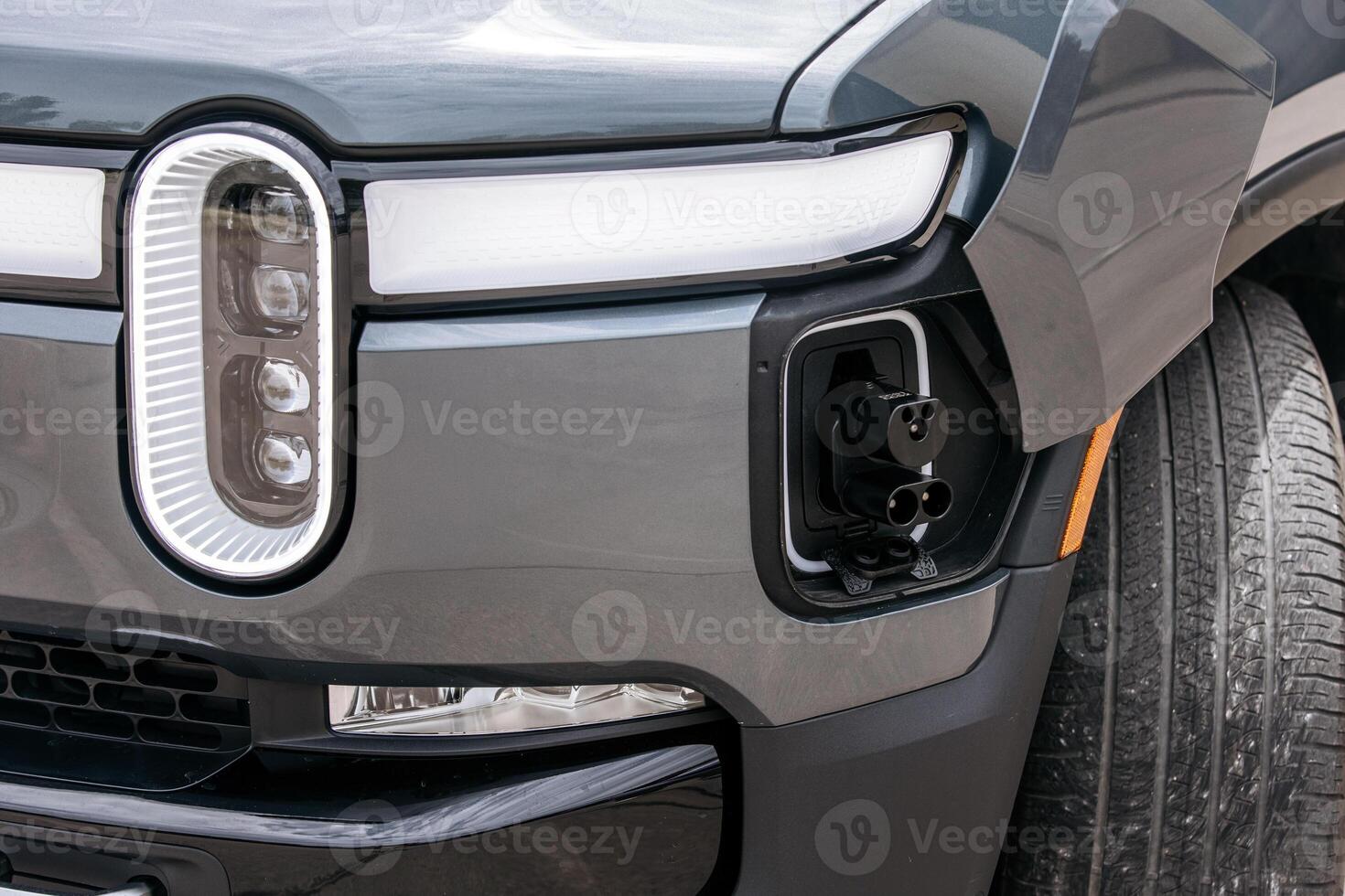 Close-up of the charging port in an electric vehicle near the headlight. The details of the port are clearly visible, highlighting the modernity and technology of the car. photo