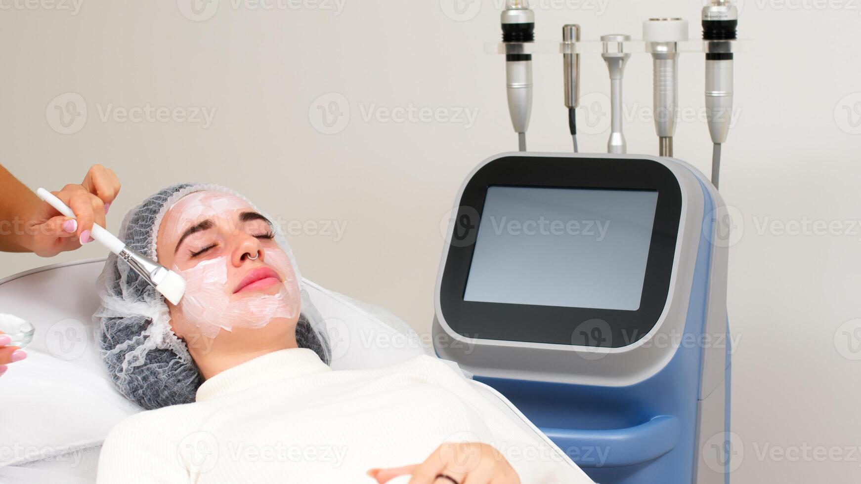 Professional cosmetologist makes a moisturizing mask on the face in a beauty salon. Spa and relaxation concept photo
