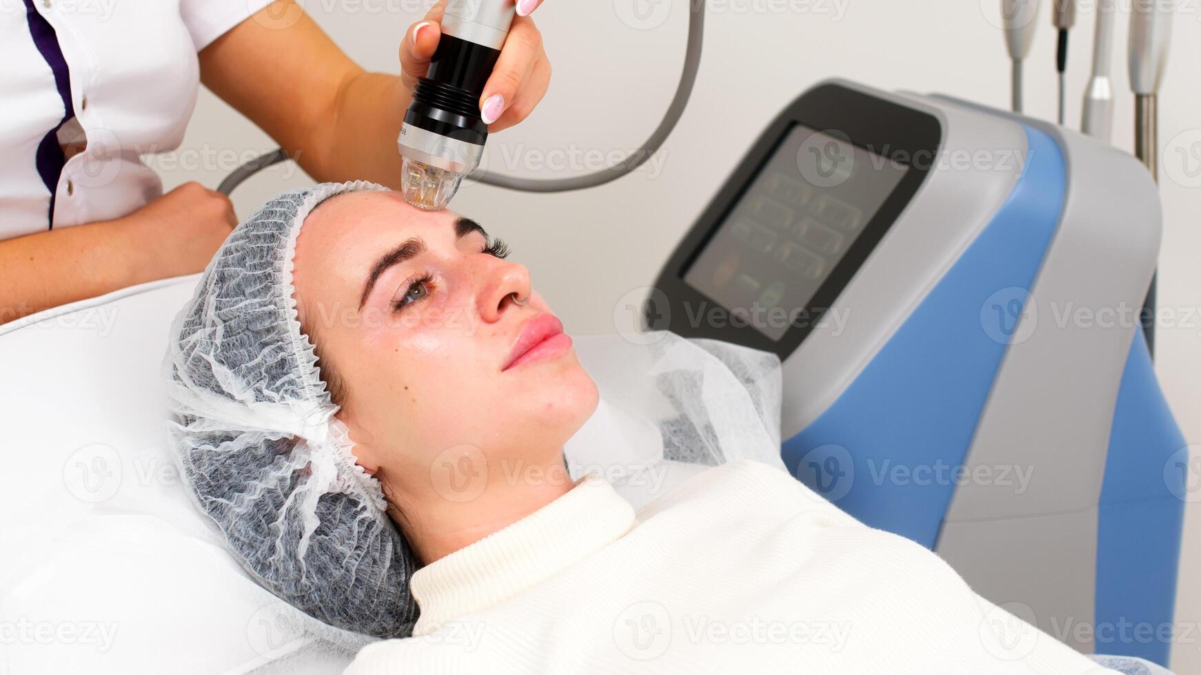Fractional microneedle RF lifting procedure in beauty clinic. Hardware cosmetology. Close up. Beautician making facial rejuvenation treatment. photo