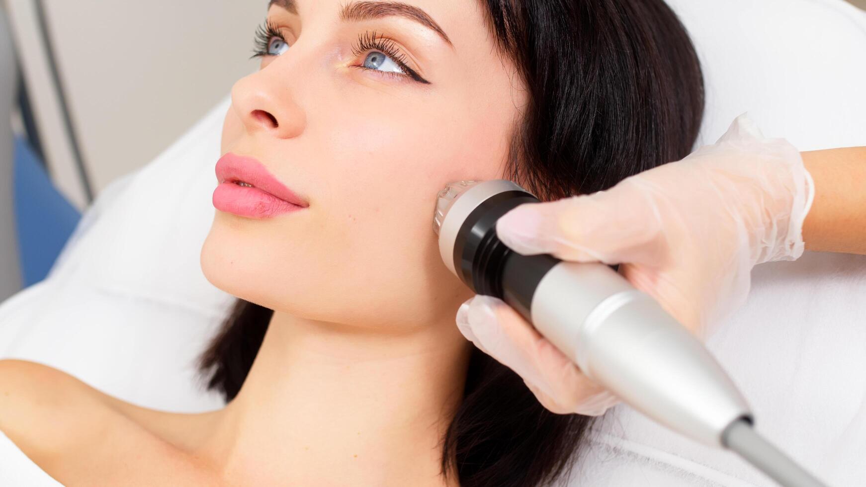 Young woman undergoing fractional radiofrequency therapy for skin rejuvenation in a medical center. Ideal for demonstrating advanced cosmetic procedures. photo
