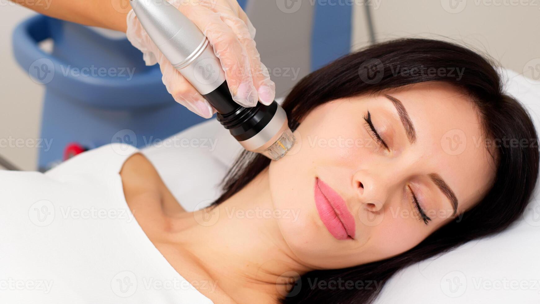 Young woman undergoing fractional radiofrequency facelift in medical center, skin rejuvenation concept. Cosmetic procedures advertising concept. photo