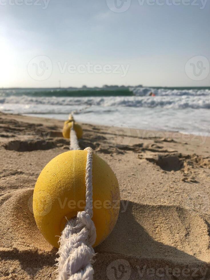 Small yellow buoy on a beach in Dubai at day with sky photo