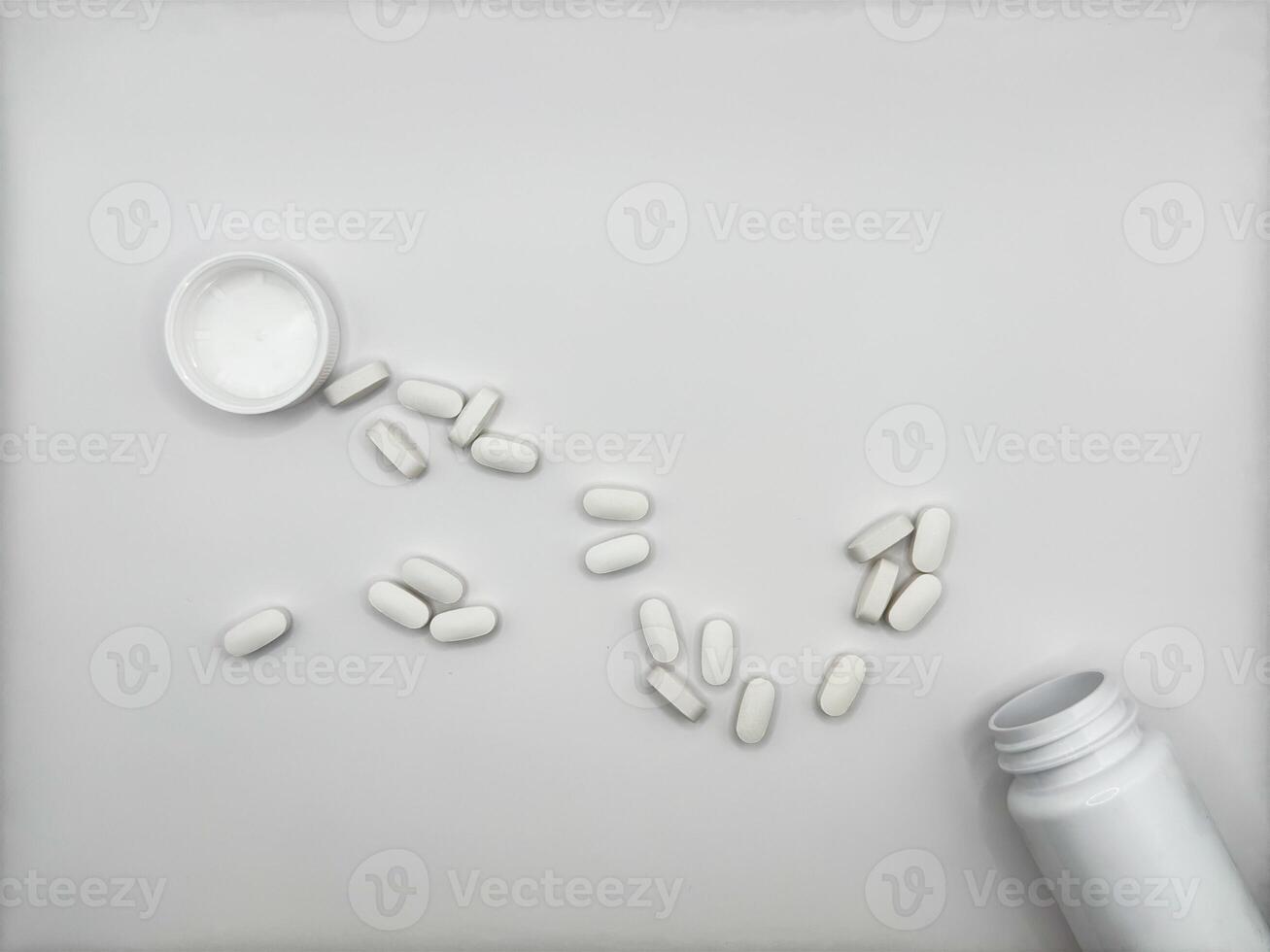 White pills for illness lie on white background spilled out of white medicine jar surface front view photo