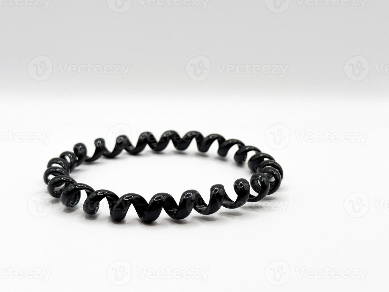 Black glossy silicone hair elastic spiral macro shot on white background front view photo