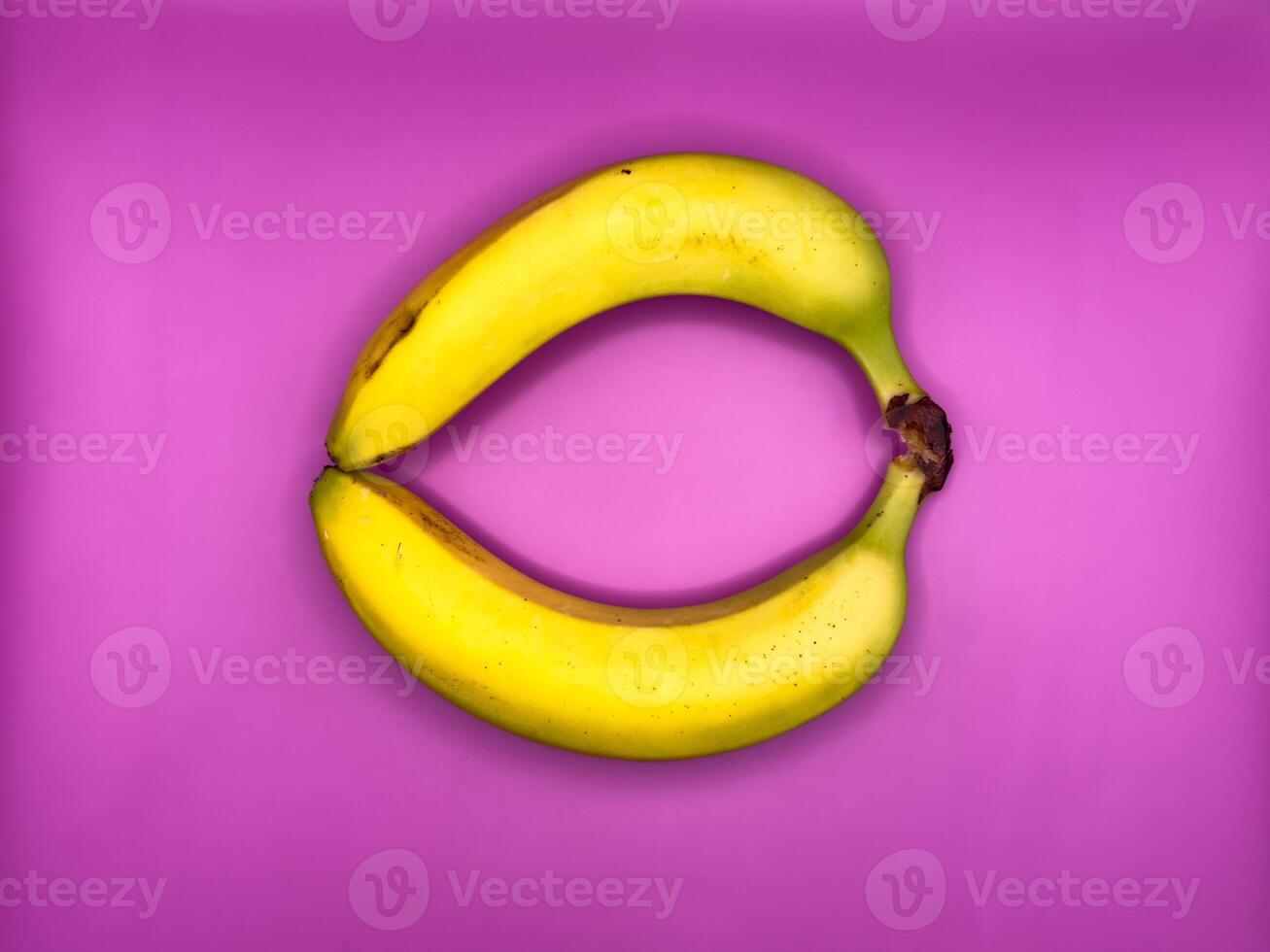 Two bright yellow bananas create a circle, top view, centered in the image photo
