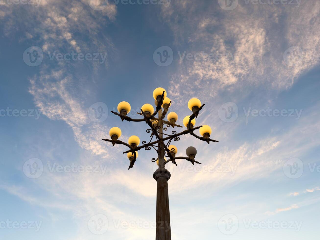 Streetlights illuminate in the late afternoon against a backdrop of cloudy blue skies. The twilight atmosphere creates a beautiful and aesthetic view. The unique pole design photo