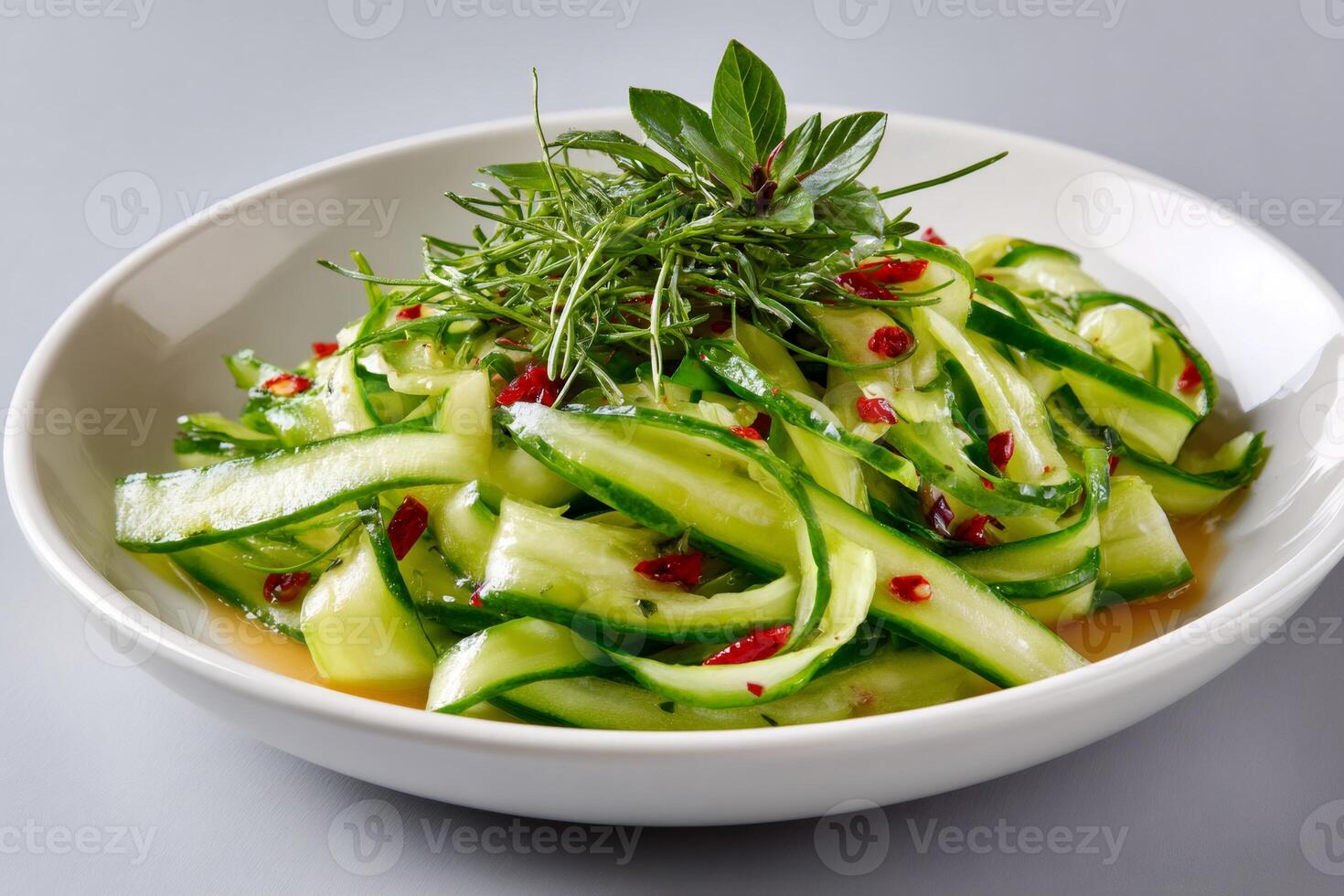 Cucumber salad with dill, basil and chili pepper flakes decorating a white plate photo