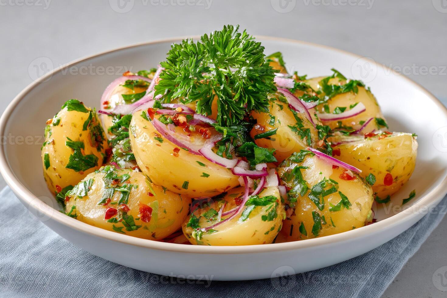 Potato salad with red onion, parsley and chili flakes dressing in a white bowl photo