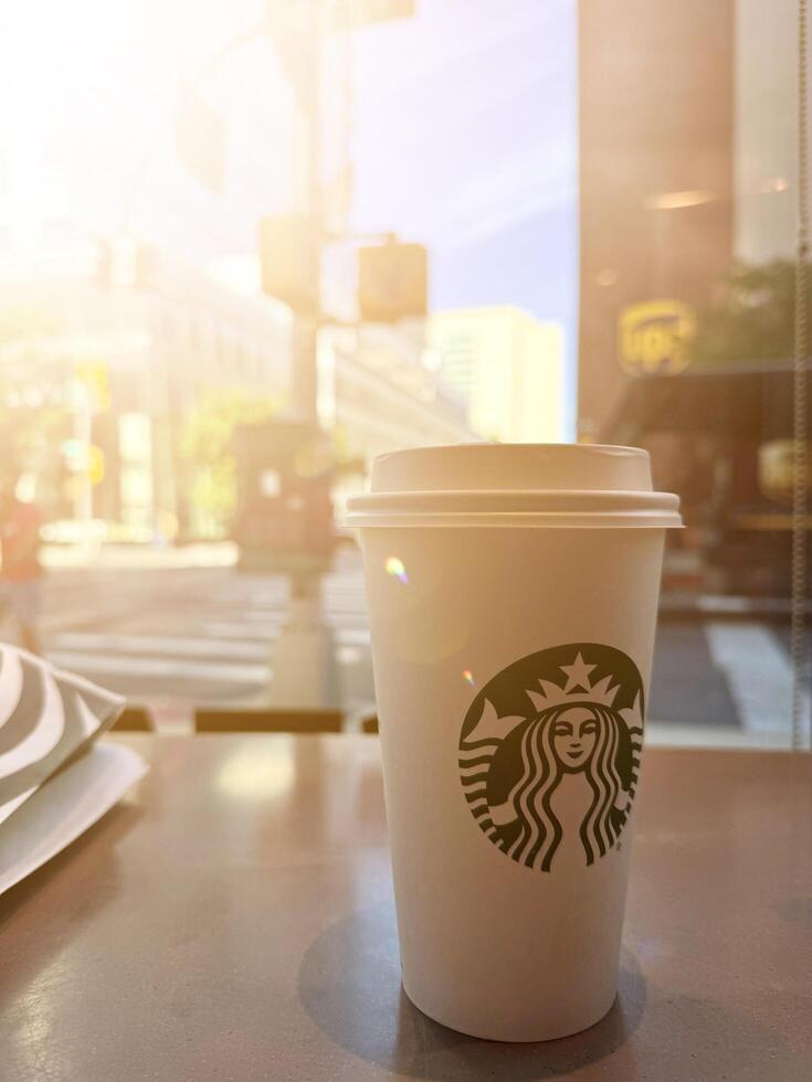 New York, USA - September 11, 2024 Close up of a tall Starbucks coffee in Starbucks coffee shop with carrot cake. photo