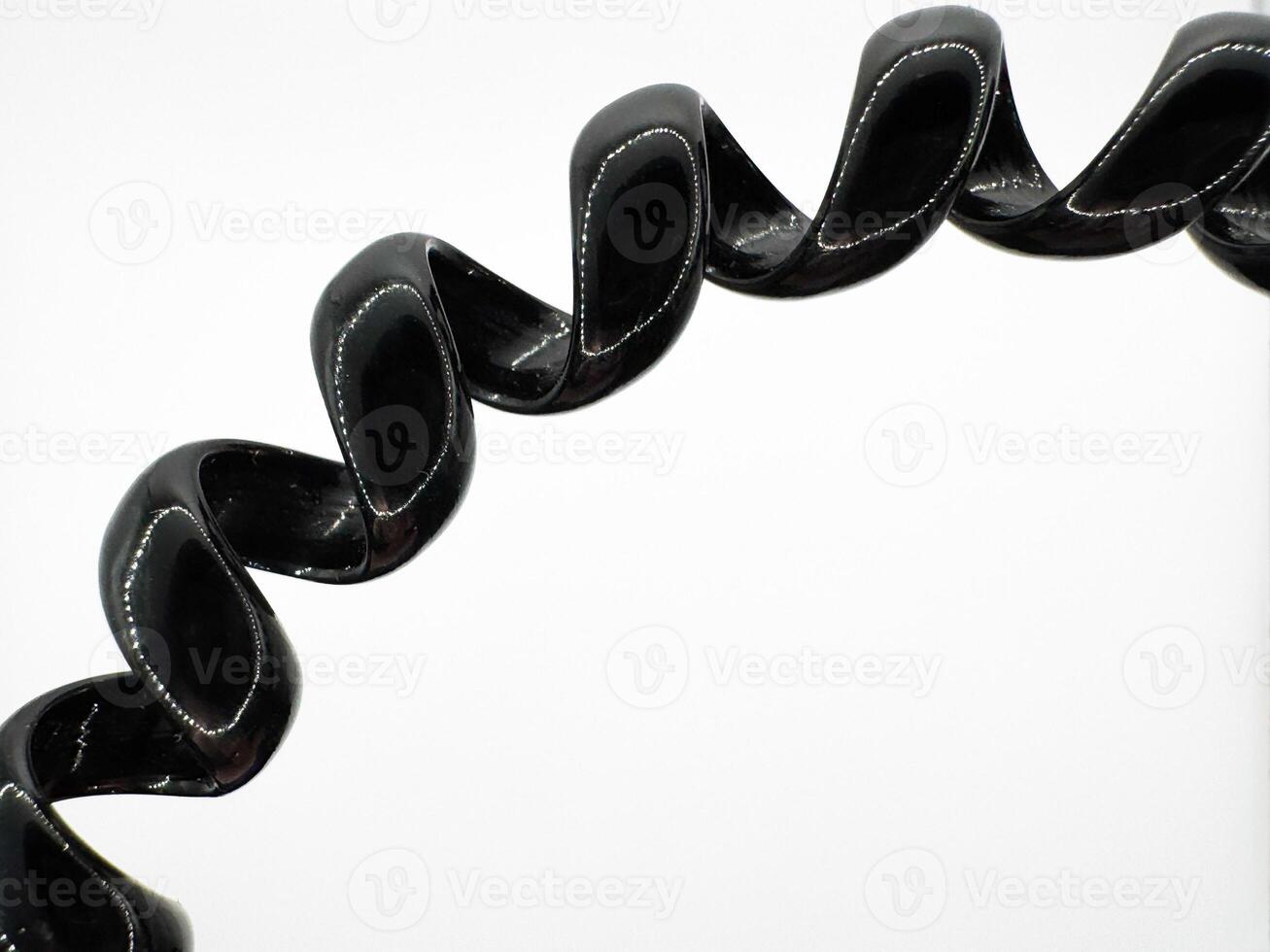 Part of black hair elastic made of glossy silicone in the form of a spiral macro shot on a white background top view photo