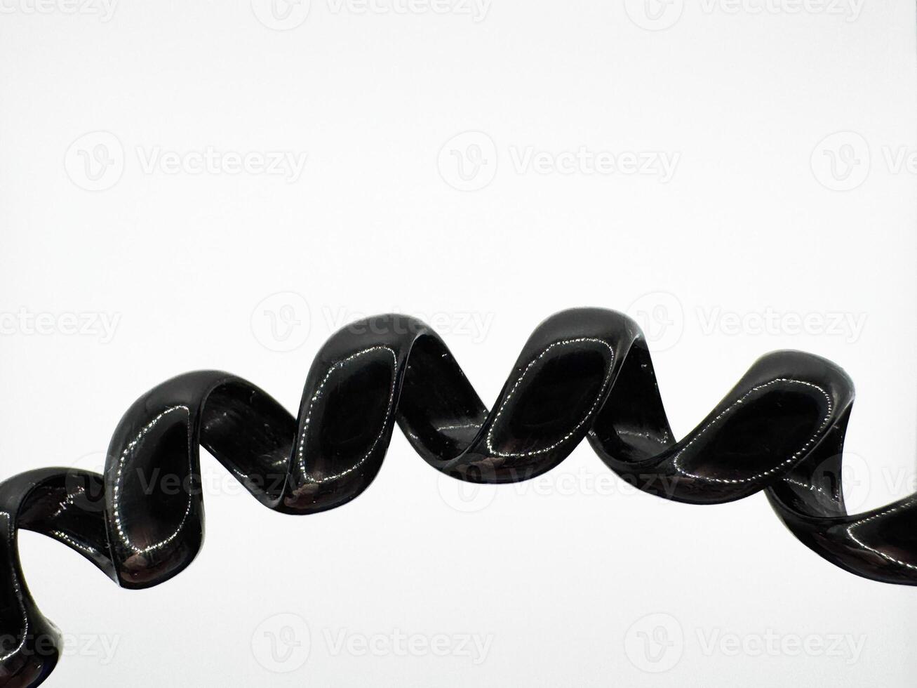 Part of a black hair elastic made of glossy silicone in the form of a spiral macro shot on a white background in the center top view photo
