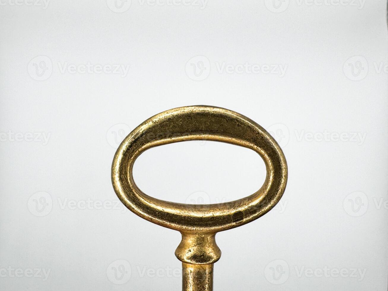 Golden metal key from an old chest on a white background in the center of the image top view photo