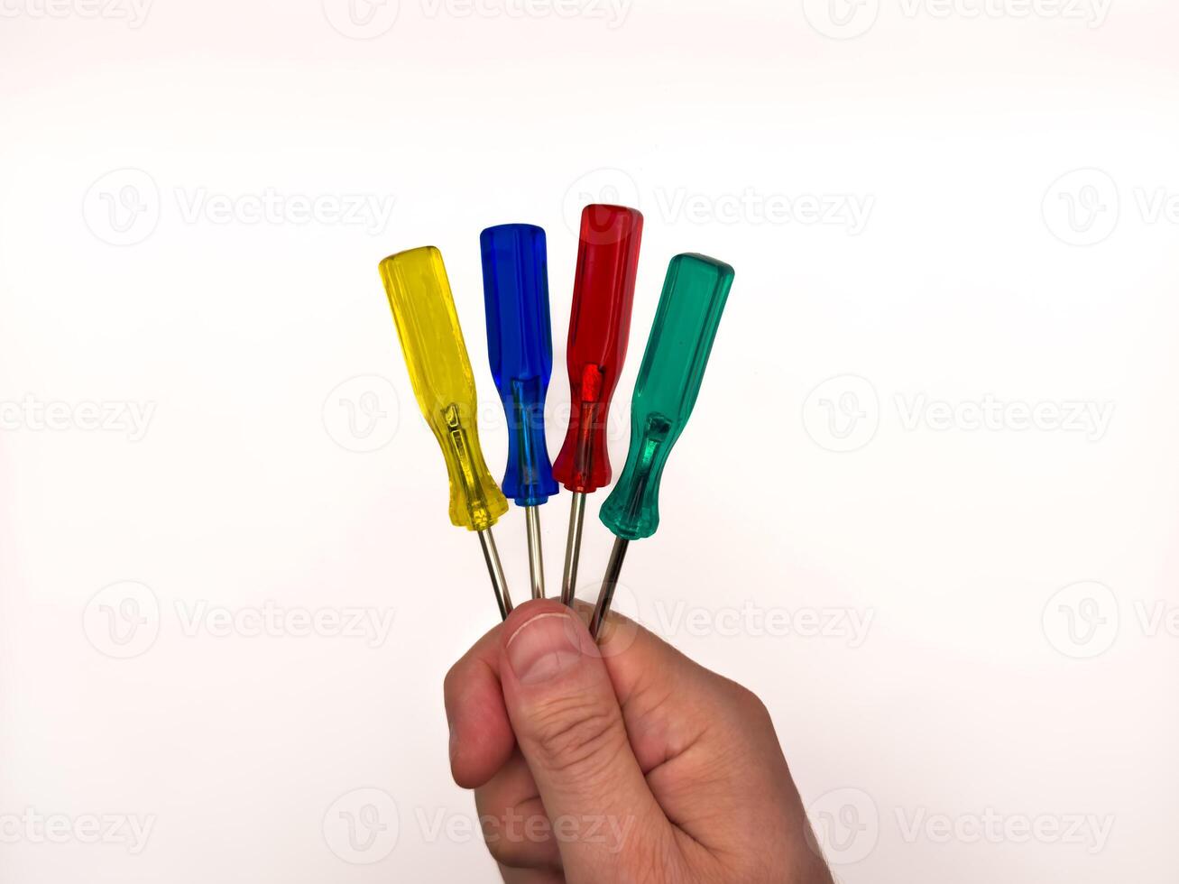 Man hand and four small colored plastic screwdrivers on a white background. copy space, flay lay, top view photo