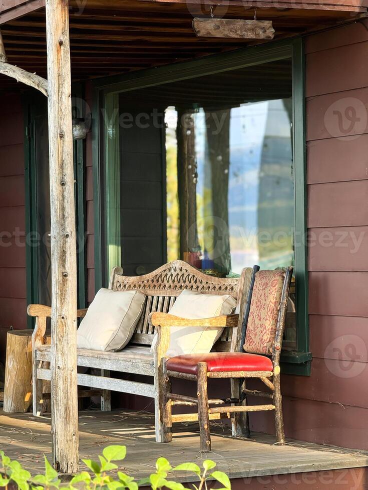 Empty chair and bench near house on lake shore with large window on veranda photo