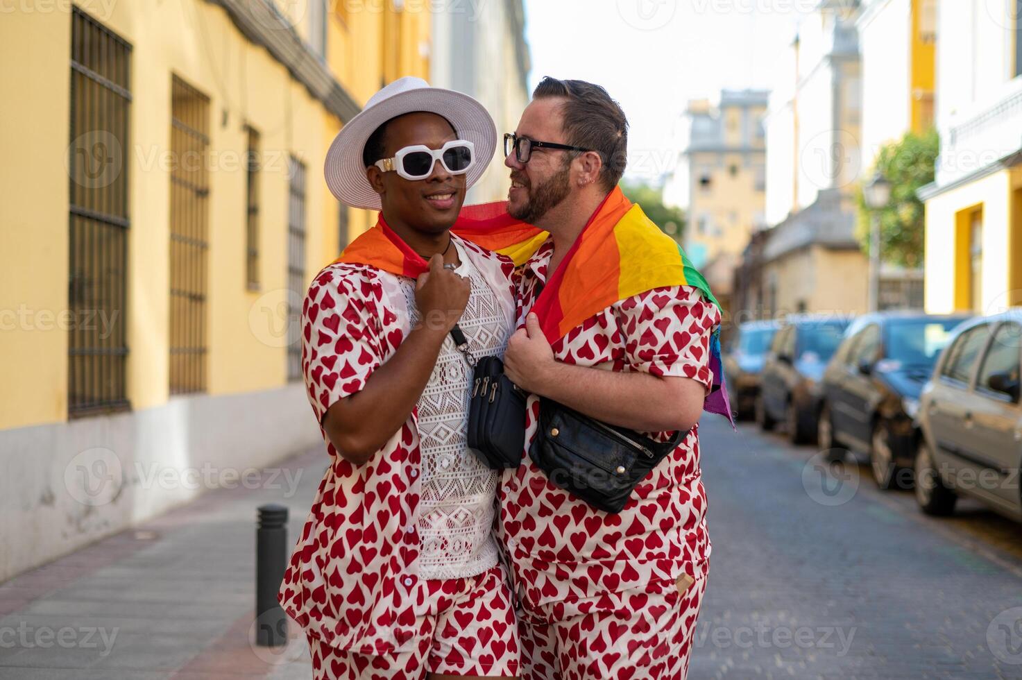Portrait of a multi-ethnic gay couple raising lgbt flag in the street in love photo