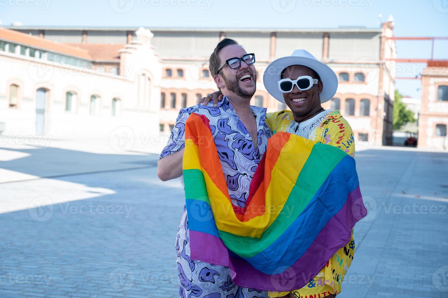 Portrait of a multi-ethnic gay couple raising lgbt flag. photo