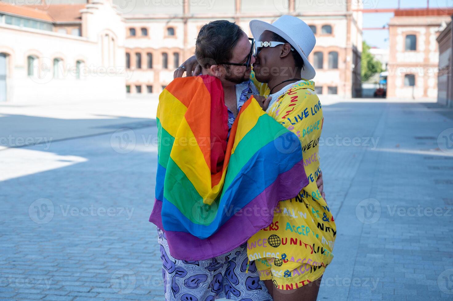 Portrait of a multi-ethnic gay couple raising lgbt flag in the street, photo