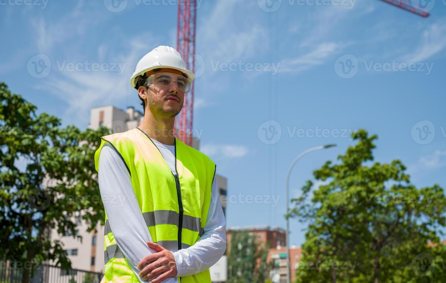Professional male construction worker with safety helmet and reflective vest and safety glasses at a construction site with building progress timeless5 photo