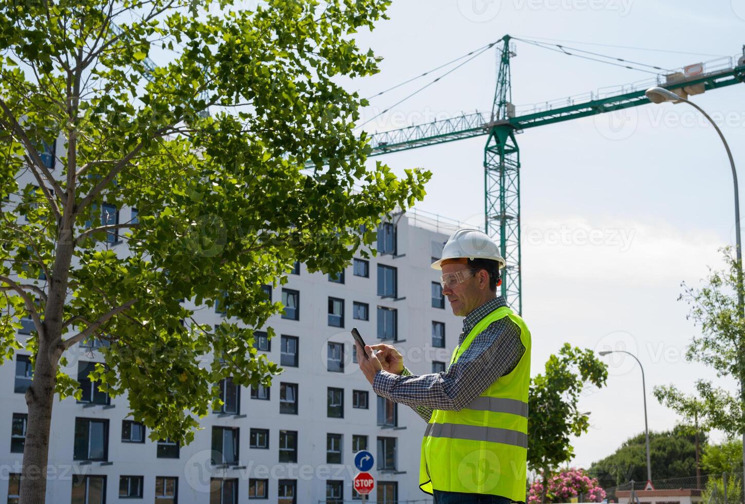Professional male construction worker with safety helmet and reflective vest and safety glasses at a construction site with building progress4 photo