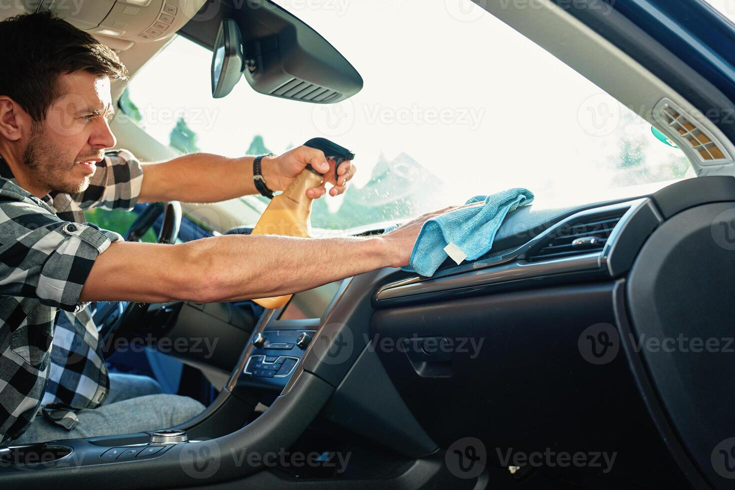 Person Cleaning Car Dashboard with Spray and Cloth photo