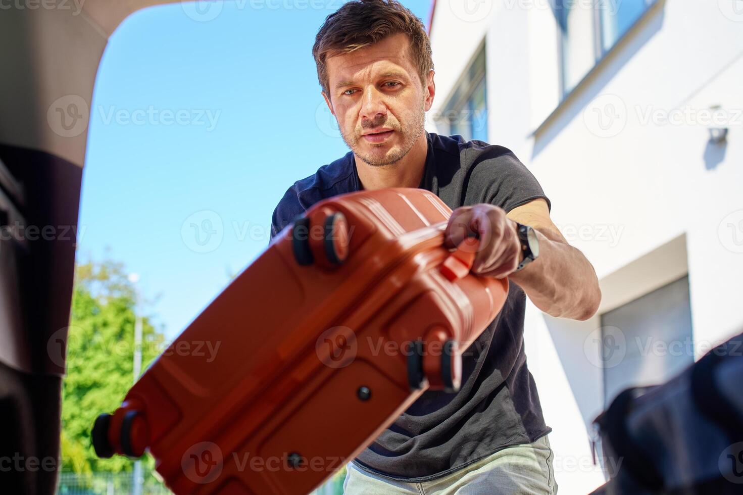 Man loading suitcase in car before travel departure photo