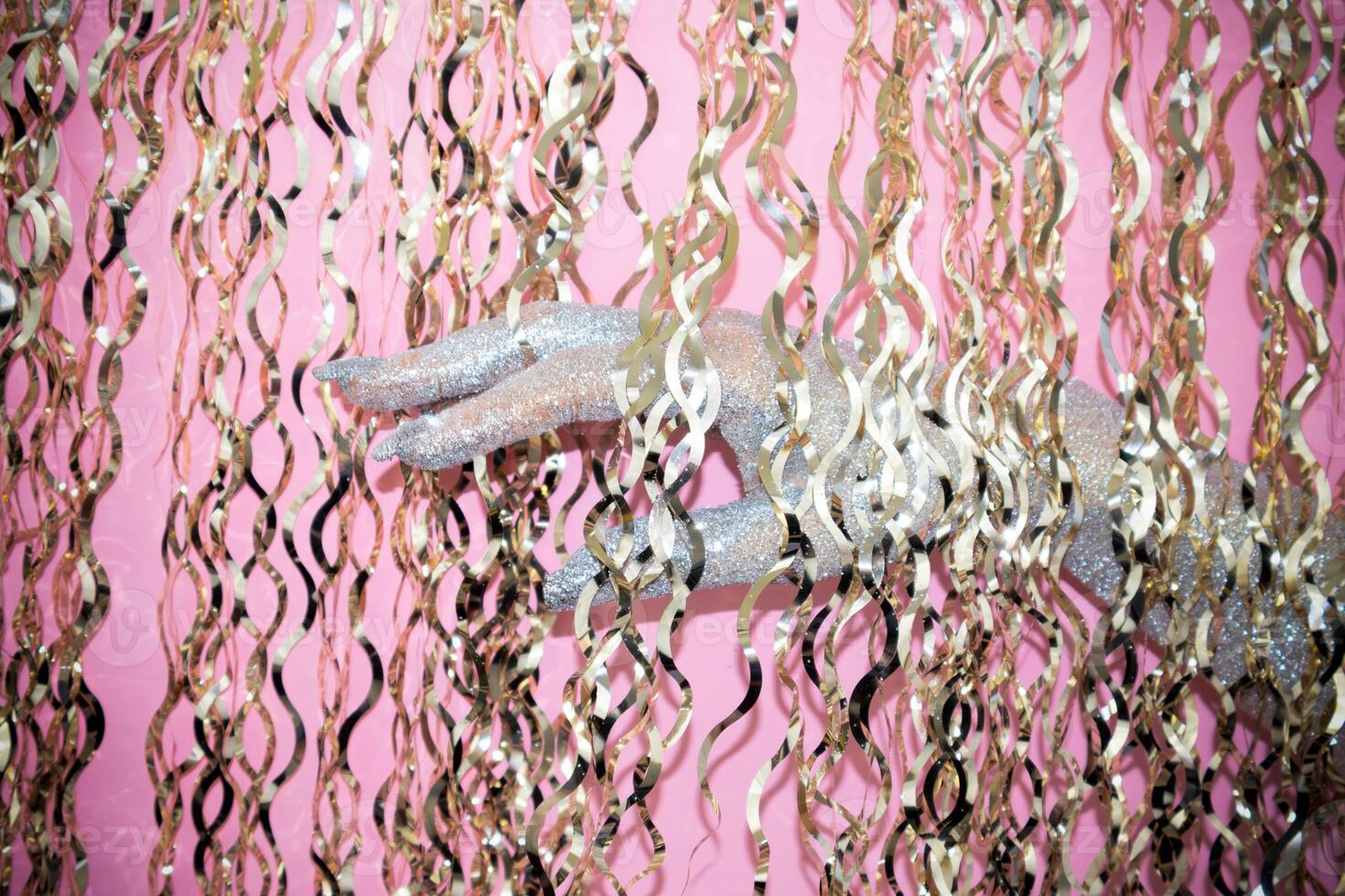 Glittering hand reaches through shimmering golden ribbons in vibrant setting. photo