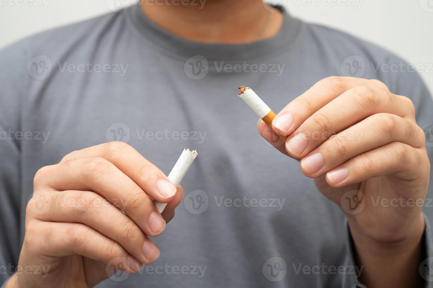 Quit smoking teenage man breaking destroy cigarette in hand. photo