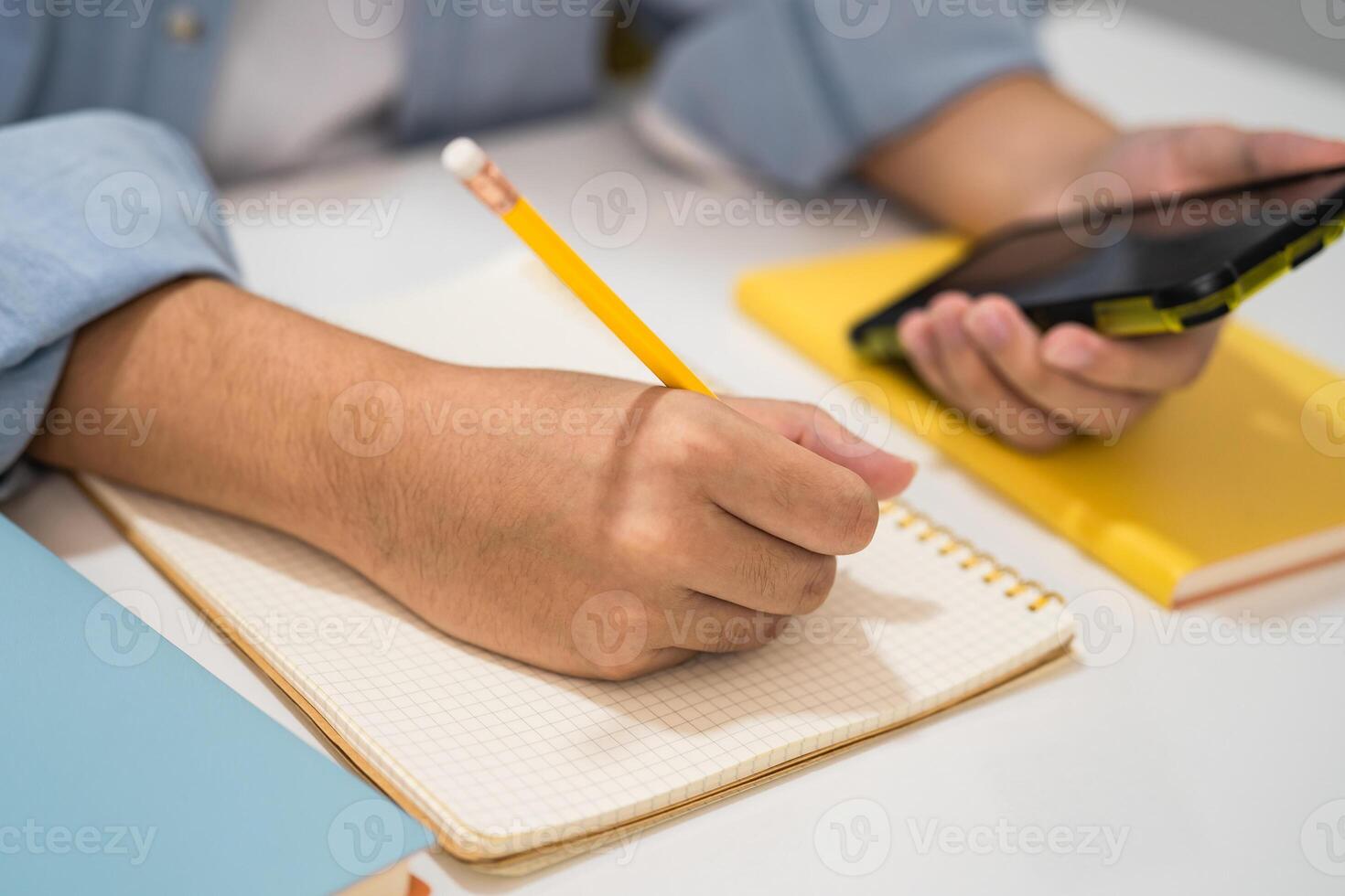 Teenage write notebook and use mobile phone search data online to online learning education. photo