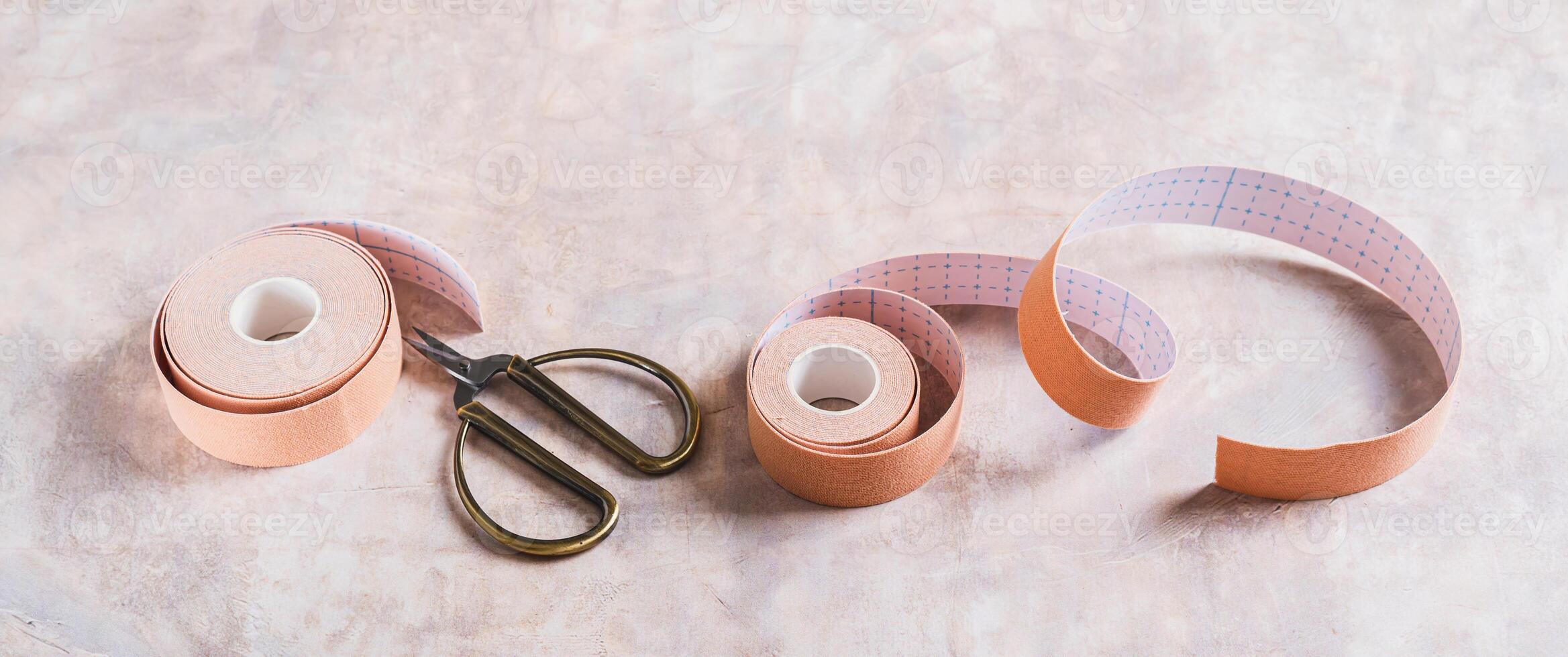 Neutral colored kinesio tapes for face lifting and scissors on the table web banner photo