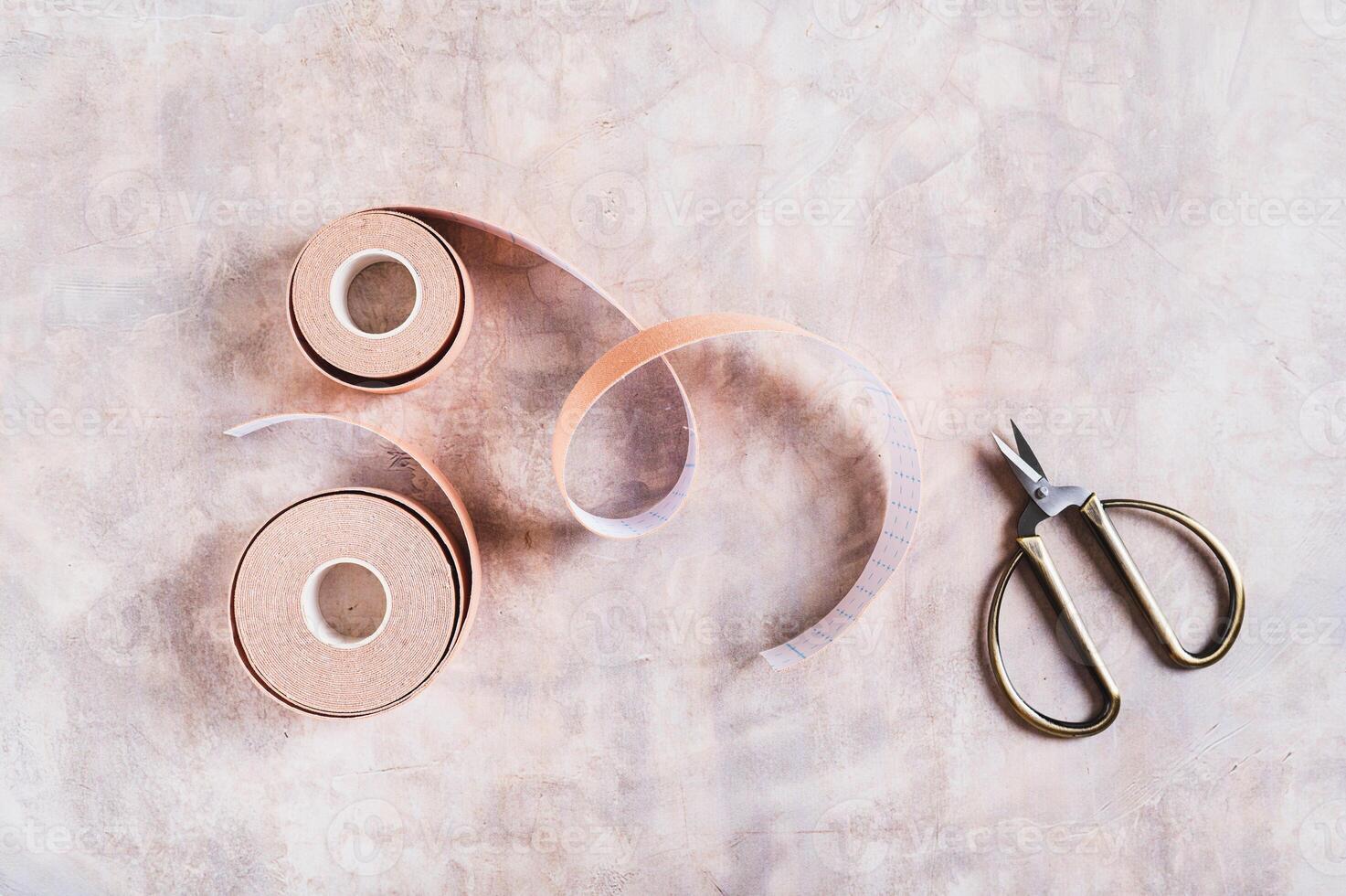 Neutral colored kinesio tapes for face lifting and scissors on the table top view photo