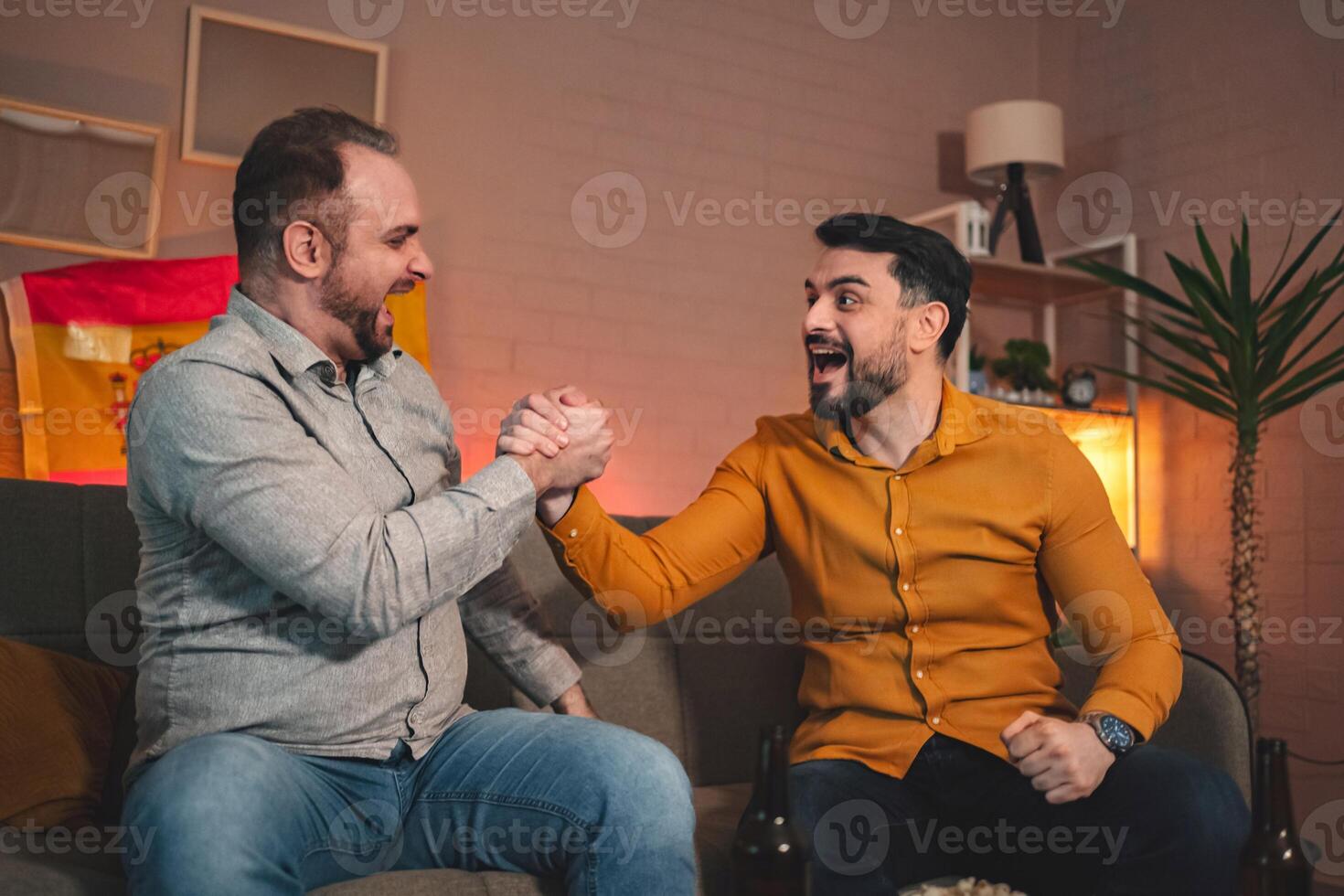 Two friends celebrate in a cozy living room while enjoying a friendly arm wrestling match during a festive gathering photo