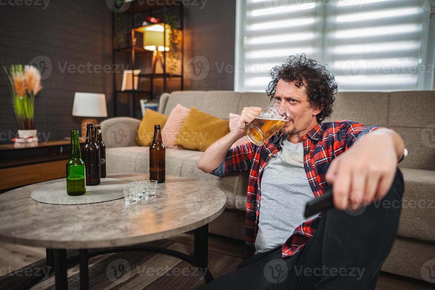 Mid adult man drinking beer and watching tv at home photo