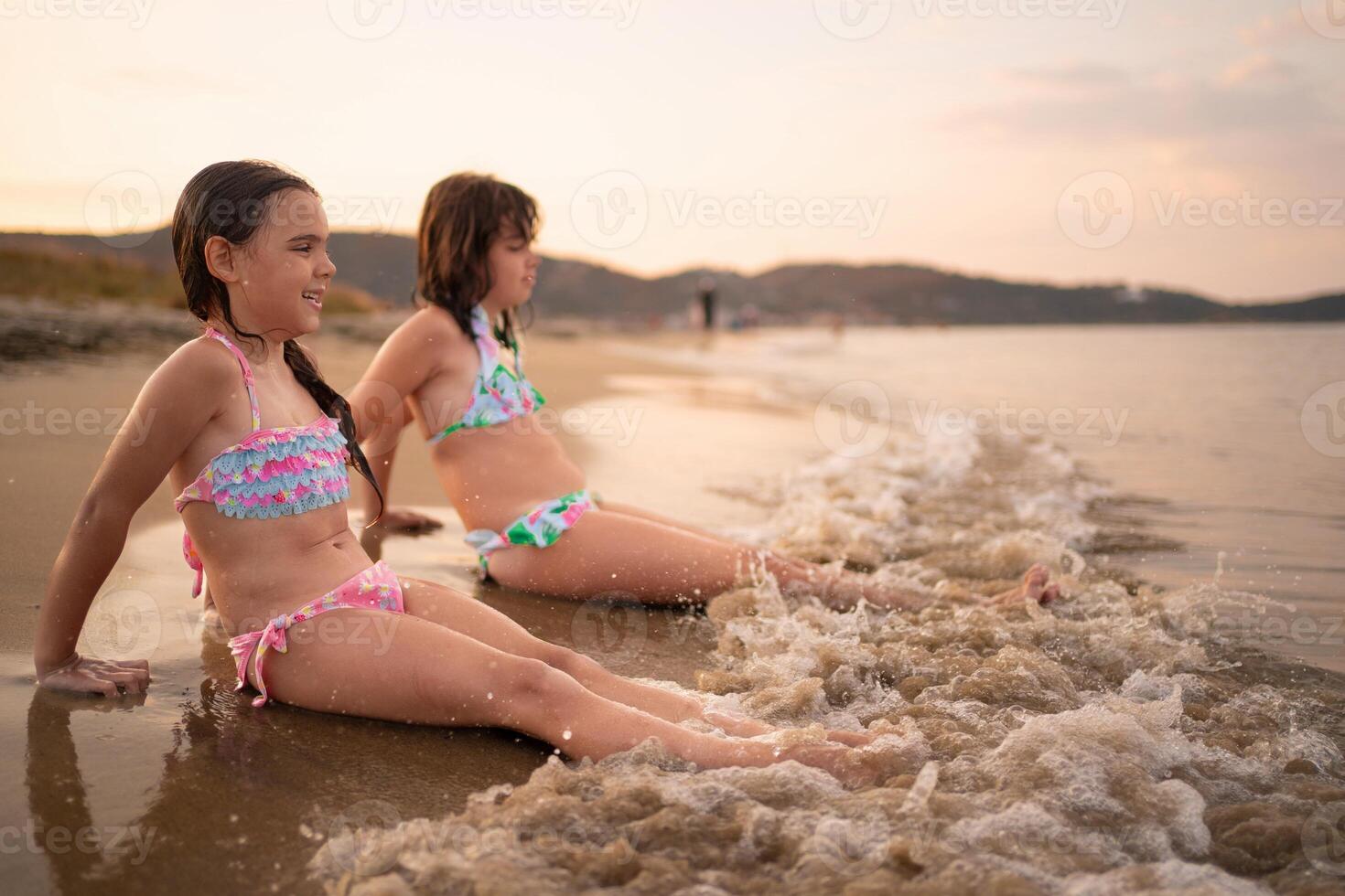 Sisters enjoying a sunny day at the beach playing with gentle waves photo