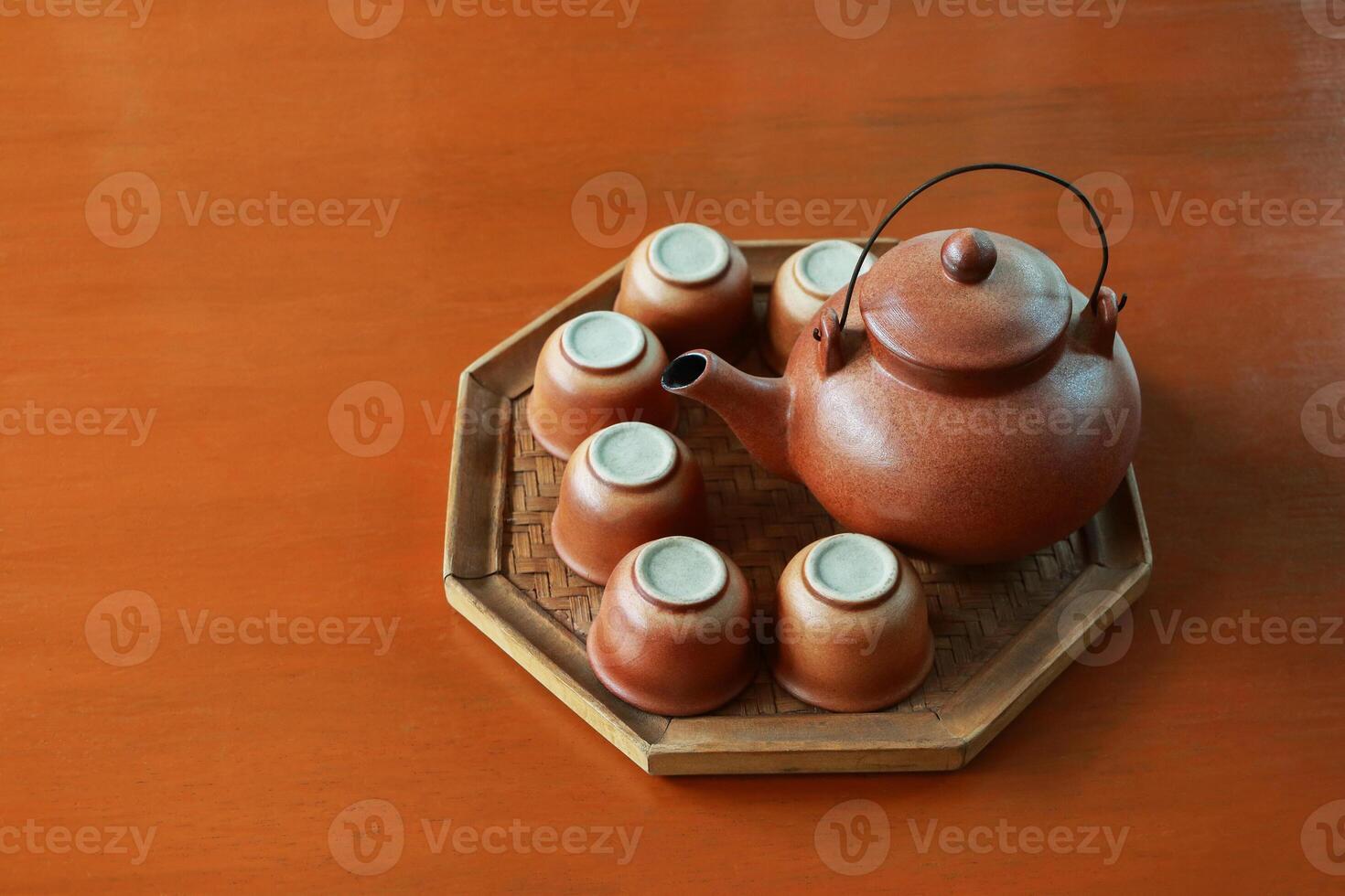 Set of baked clay kettle and cups on octagon tray. photo