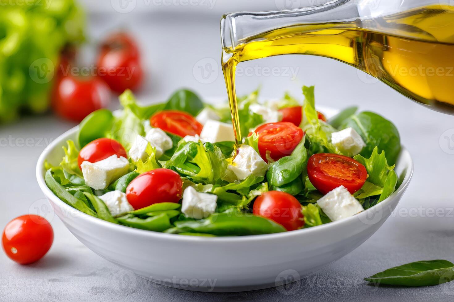 Cook pouring olive oil over fresh salad with tomatoes, cheese and lettuce photo