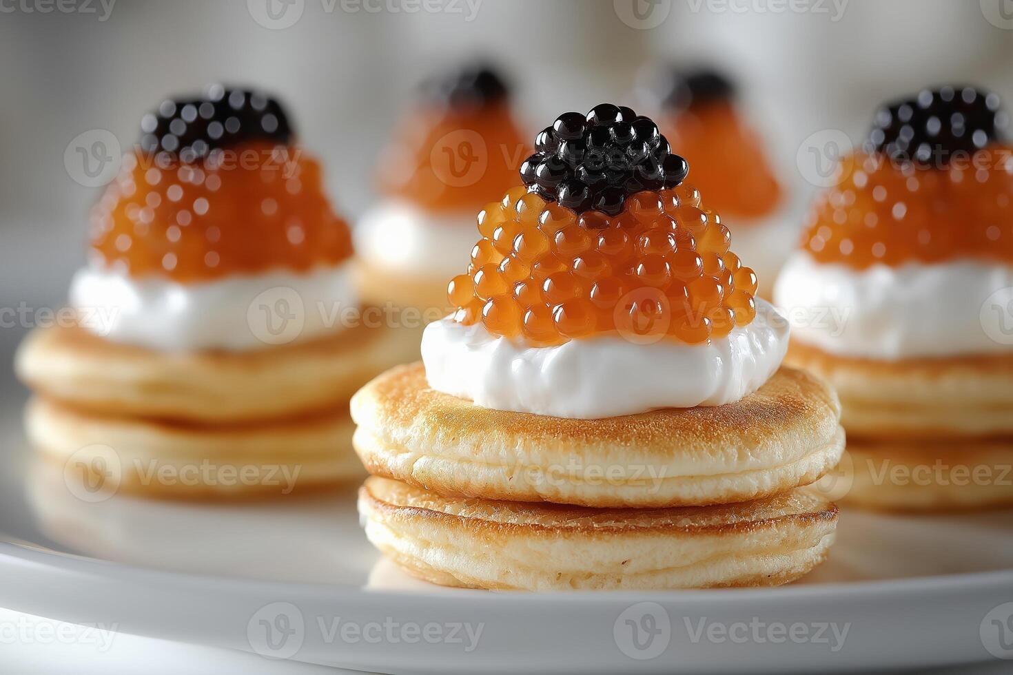 Delicious blinis with red and black caviar topping a sour cream rosette photo