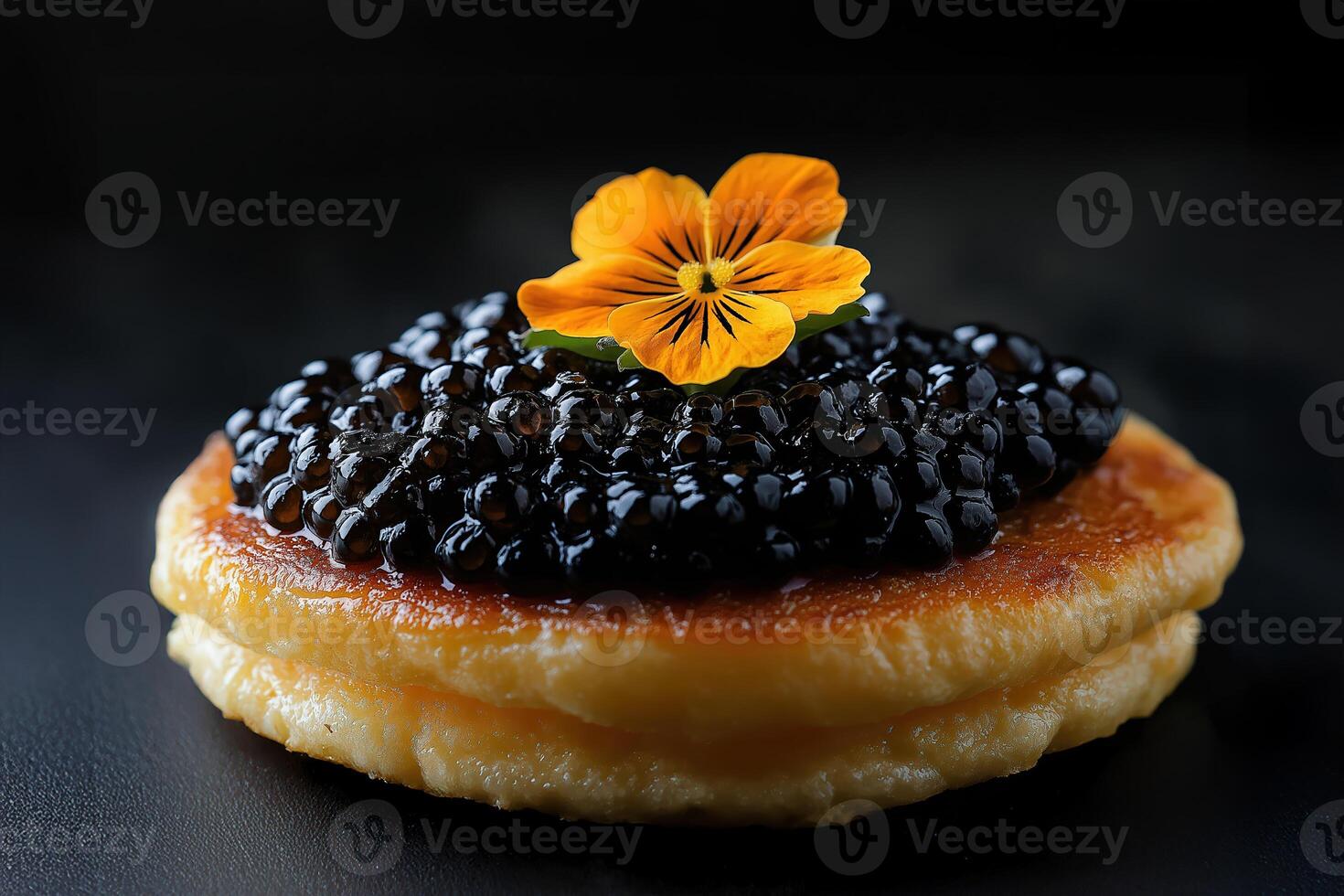 Delicious blinis with black caviar and edible flower topping, garnished and served on a dark plate photo